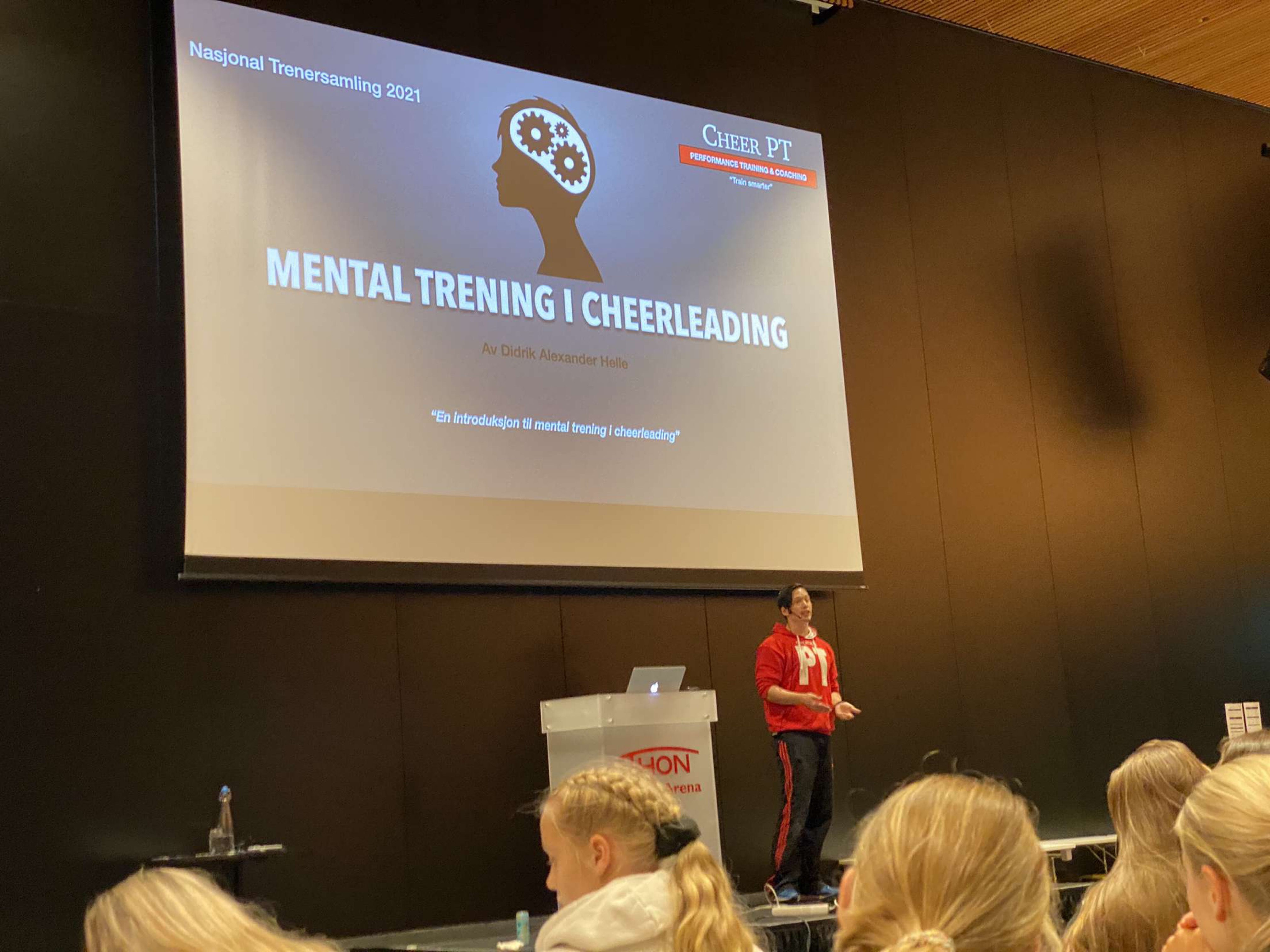 Didrik presenting Mental Training in Cheerleading at the 2021 National Cheerleading Coaches’ Gathering, with the lecture title projected beside him